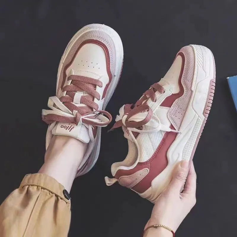 Pink and white low top women's sneakers with a rubber sole and height increasing feature.