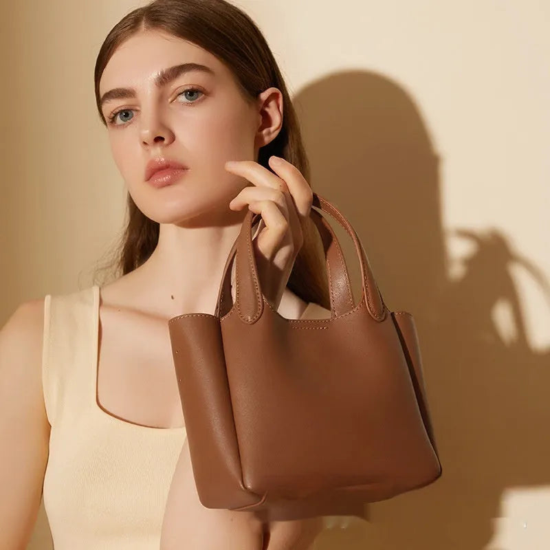 Brown genuine cattlehide leather cross body bucket bag showing sewing thread detail and slit pocket.