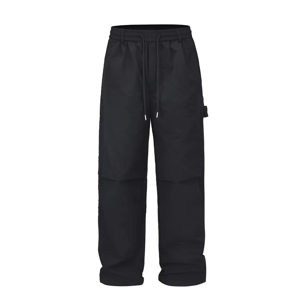 Black baggy paratrooper trousers with an elasticated drawstring waistband and three-dimensional cutting.