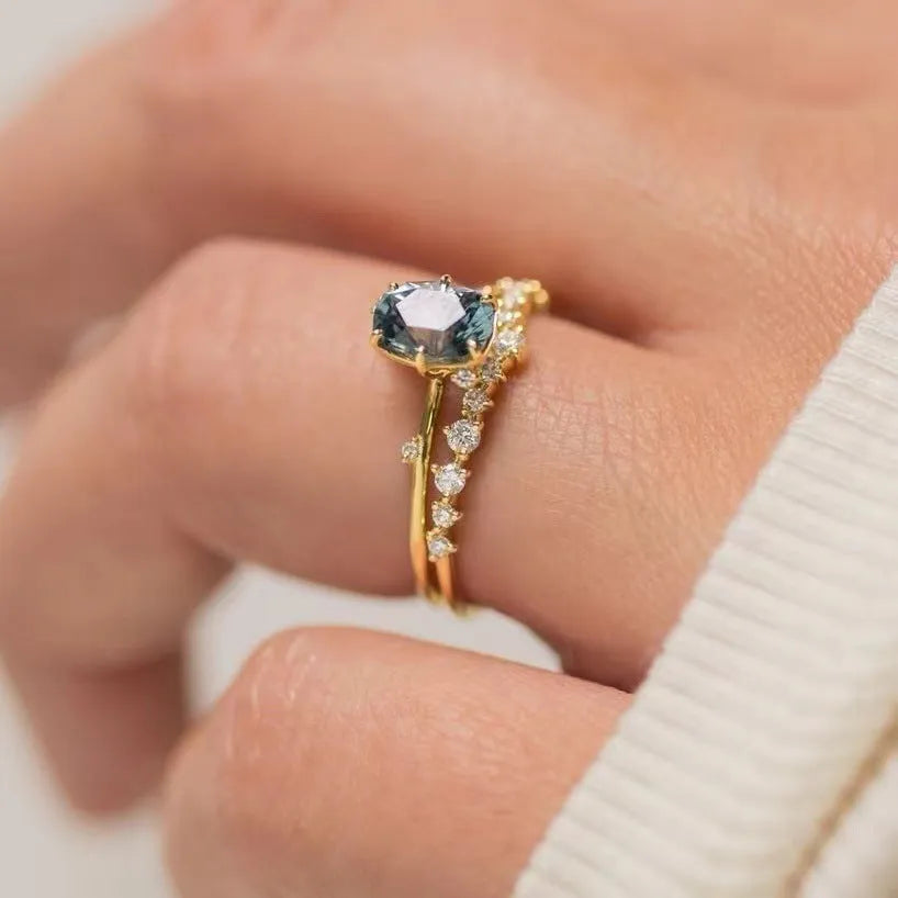 A pair of gold-plated floral rings with a central green zircon stone on a white background.