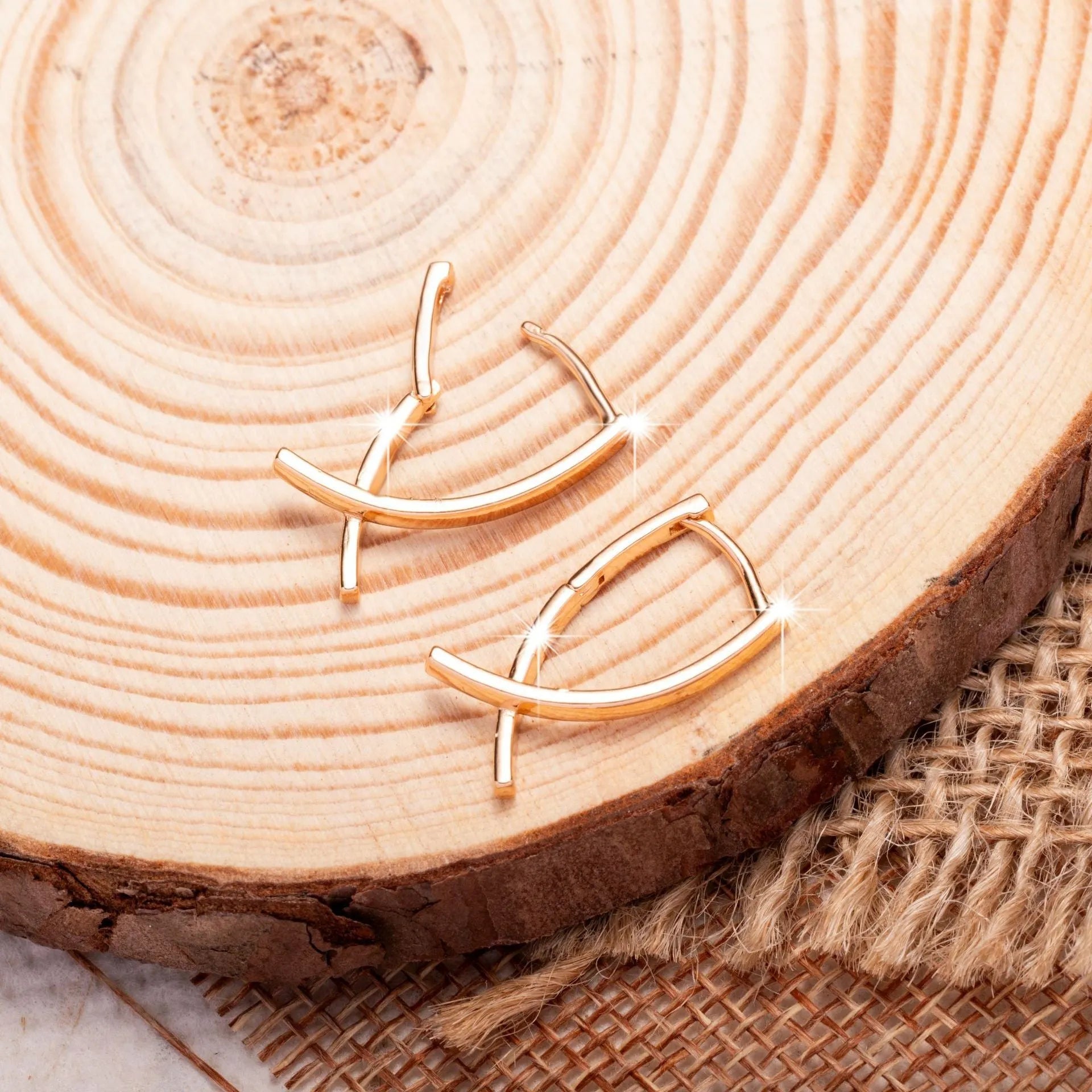 A pair of rose gold cross shaped drop earrings on a plain background.