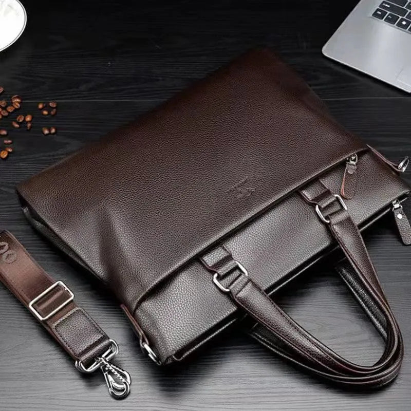 Men's black PU leather shoulder messenger bag with splicing detail on a table