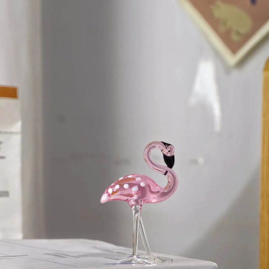 A pink flamingo decorative ornament made from clear white crystal on a table.