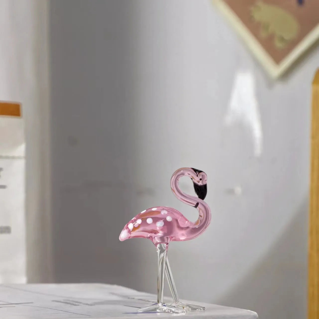 A pink flamingo decorative ornament made from clear white crystal on a table.