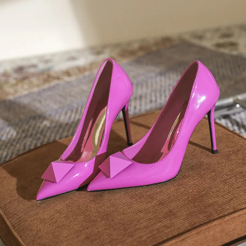 Pink women's patent leather pointed toe stiletto high heels with a buckle on the vamp.