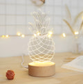 Cartoon pineapple-shaped USB table lamp with wooden base on a bedside table.