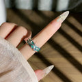 Mint green enamel eight-point asterism ring on a copper base, showing asymmetric and folded design details.