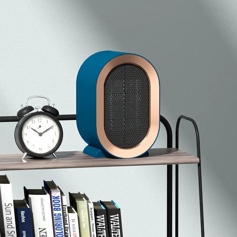 Compact black desktop electric ceramic fan heater with control knob on a wooden desk.