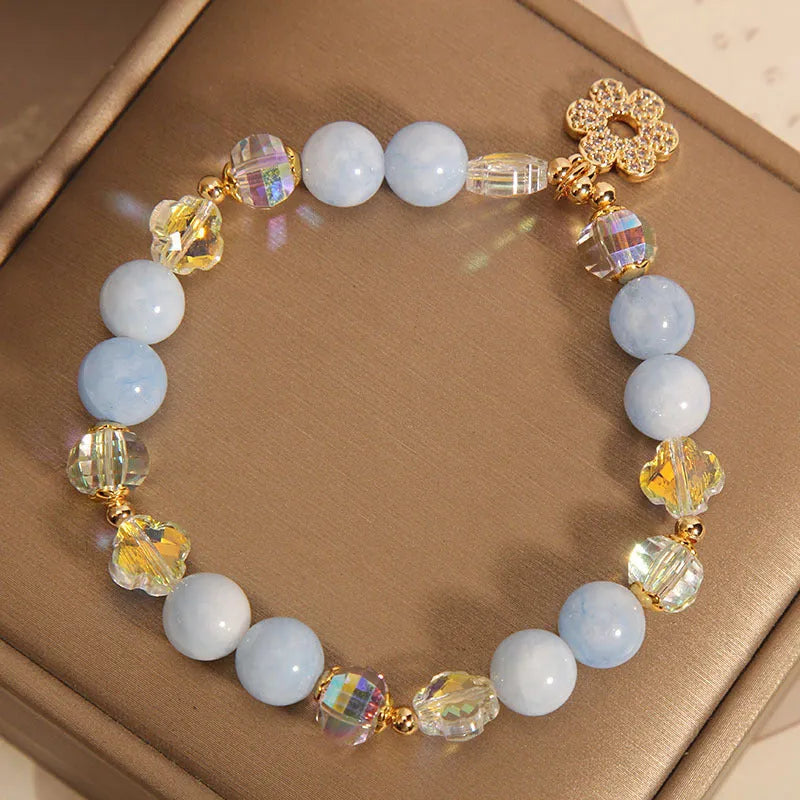 Women's aquamarine crystal bracelet with a four-leaf clover charm and small pearl accent.