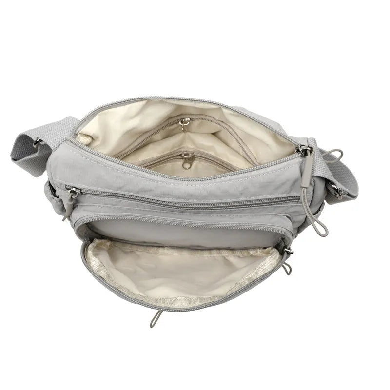 Grey water-repellent nylon crossbody bag showing three-dimensional pockets and a single shoulder strap.