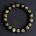 Natural obsidian crater ball bracelet with a ground texture in silver stone or gold colours on a wrist.