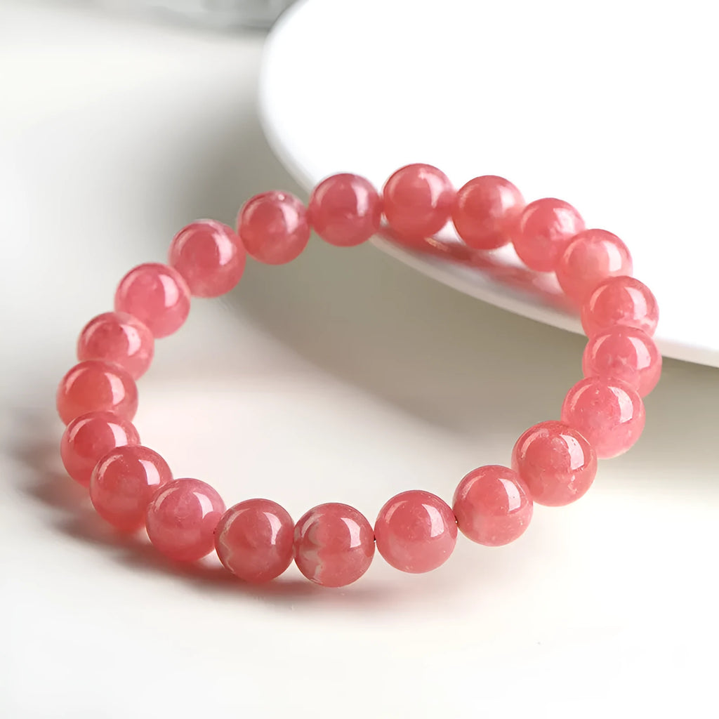 Women's red rhodochrosite crystal bracelet with geometric beads and longevity lock charm on wrist