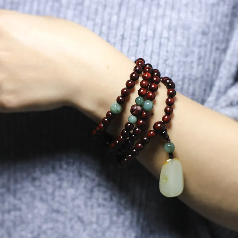Close-up of a rosewood bead bracelet with 108 beads and a carved Hotian jade pendant.