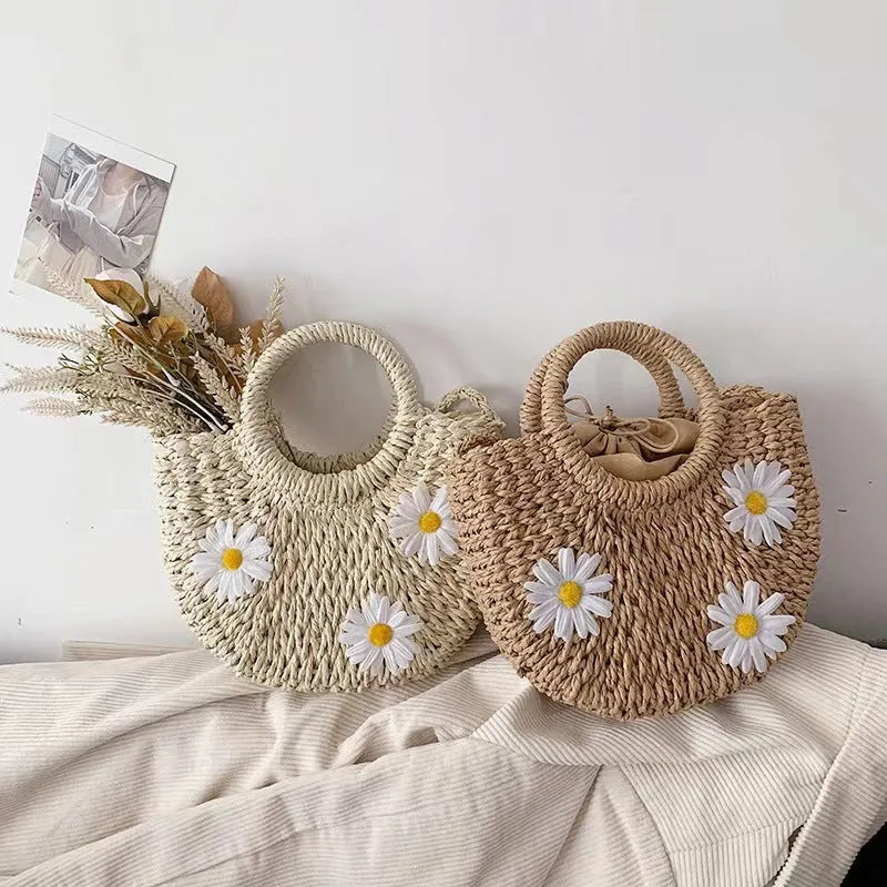 Light brown woven straw crossbody bag with daisy decoration showing shoulder strap