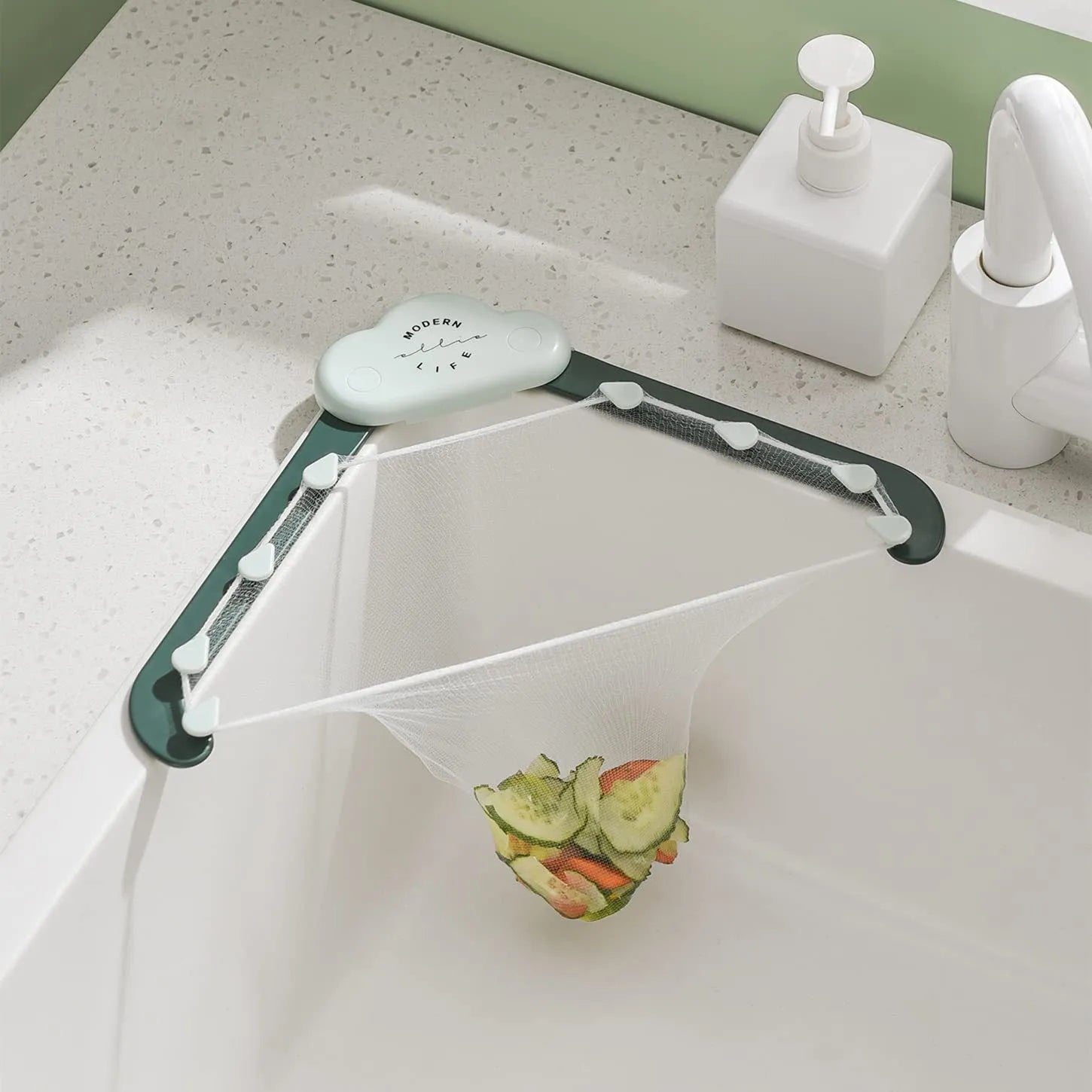 Green triangular sink drain rack with mesh filter bag installed in a kitchen sink corner