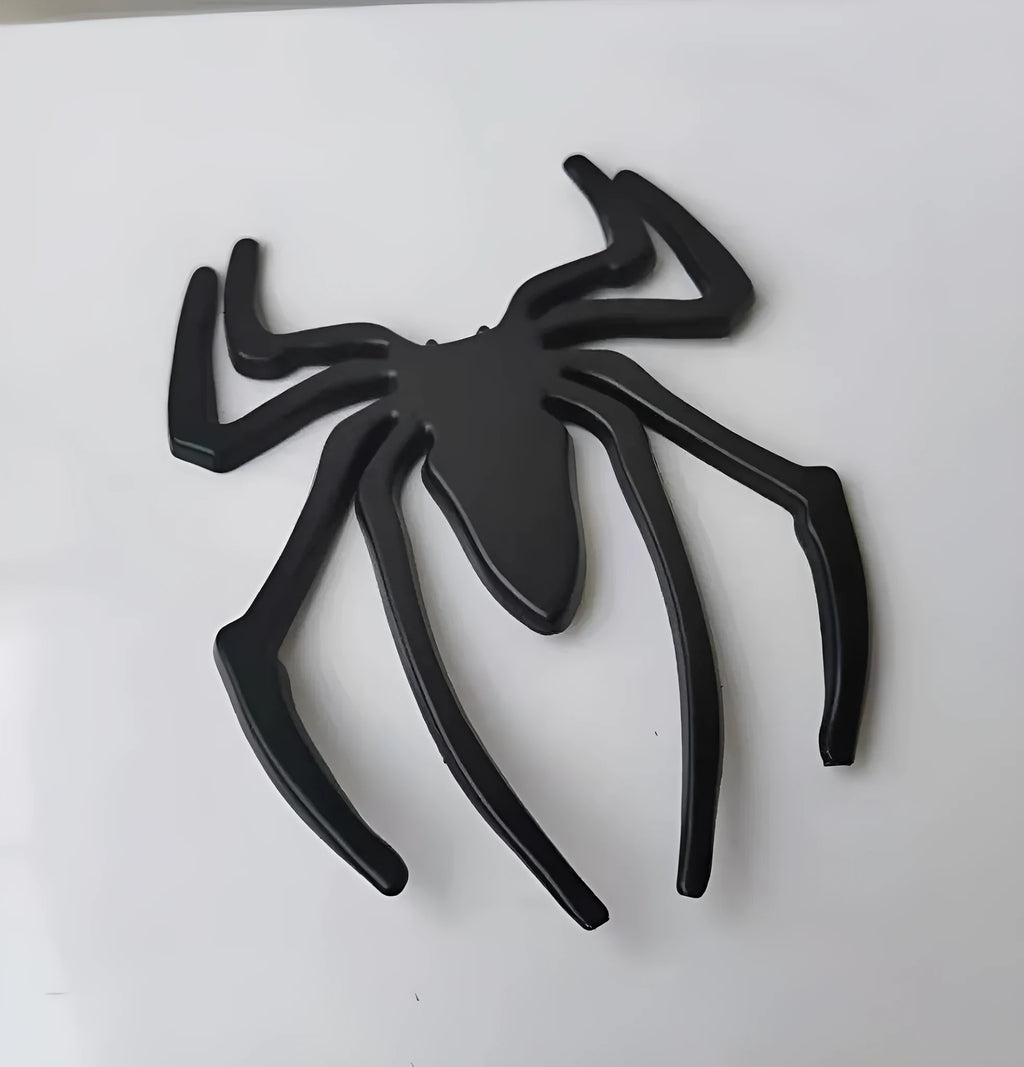 Three-dimensional metal spider bumper sticker in metallic finish.