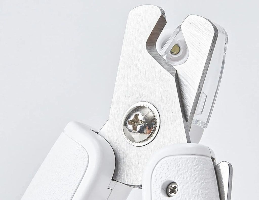 White pet nail clippers with LED light, transparent guard, and nail file on a grey background.