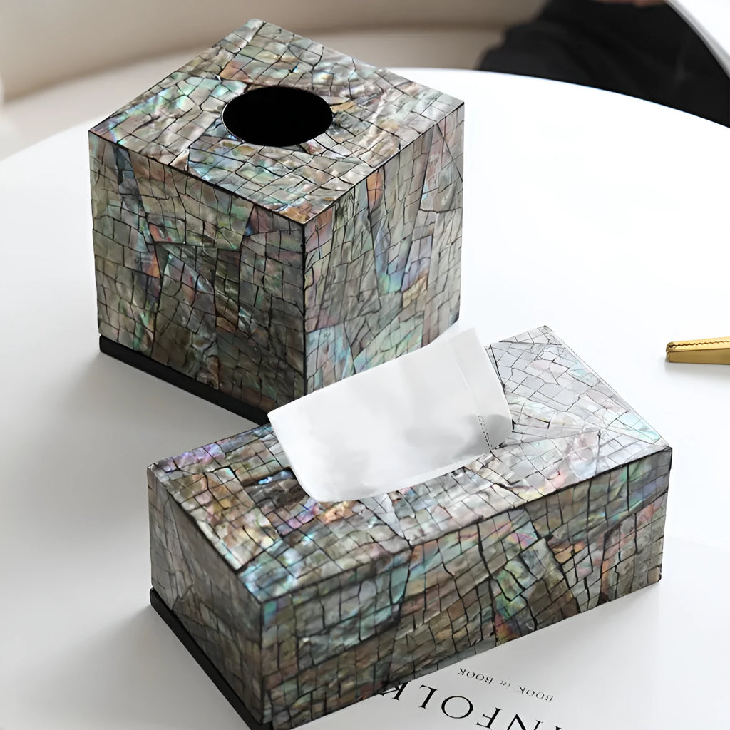 A black rectangular shell tissue box holder with a removable lid on a wooden coffee table.