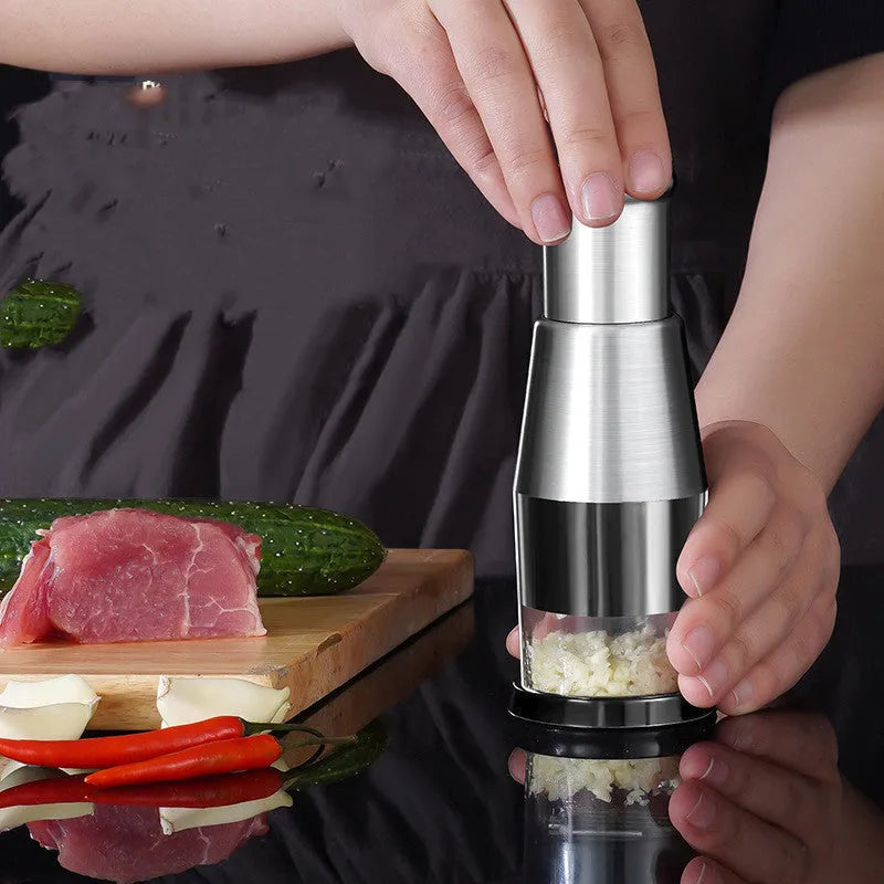 Black manual garlic crusher and onion chopper with stainless steel blades on kitchen counter