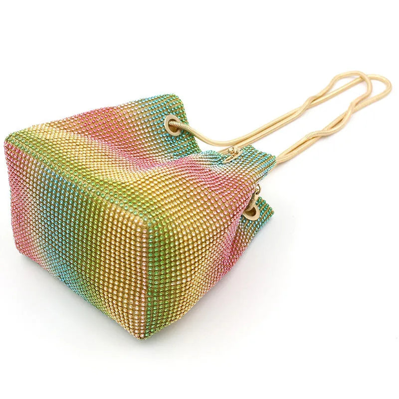 Sparkling rhinestone bucket bag with drawstring closure on a soft texture.