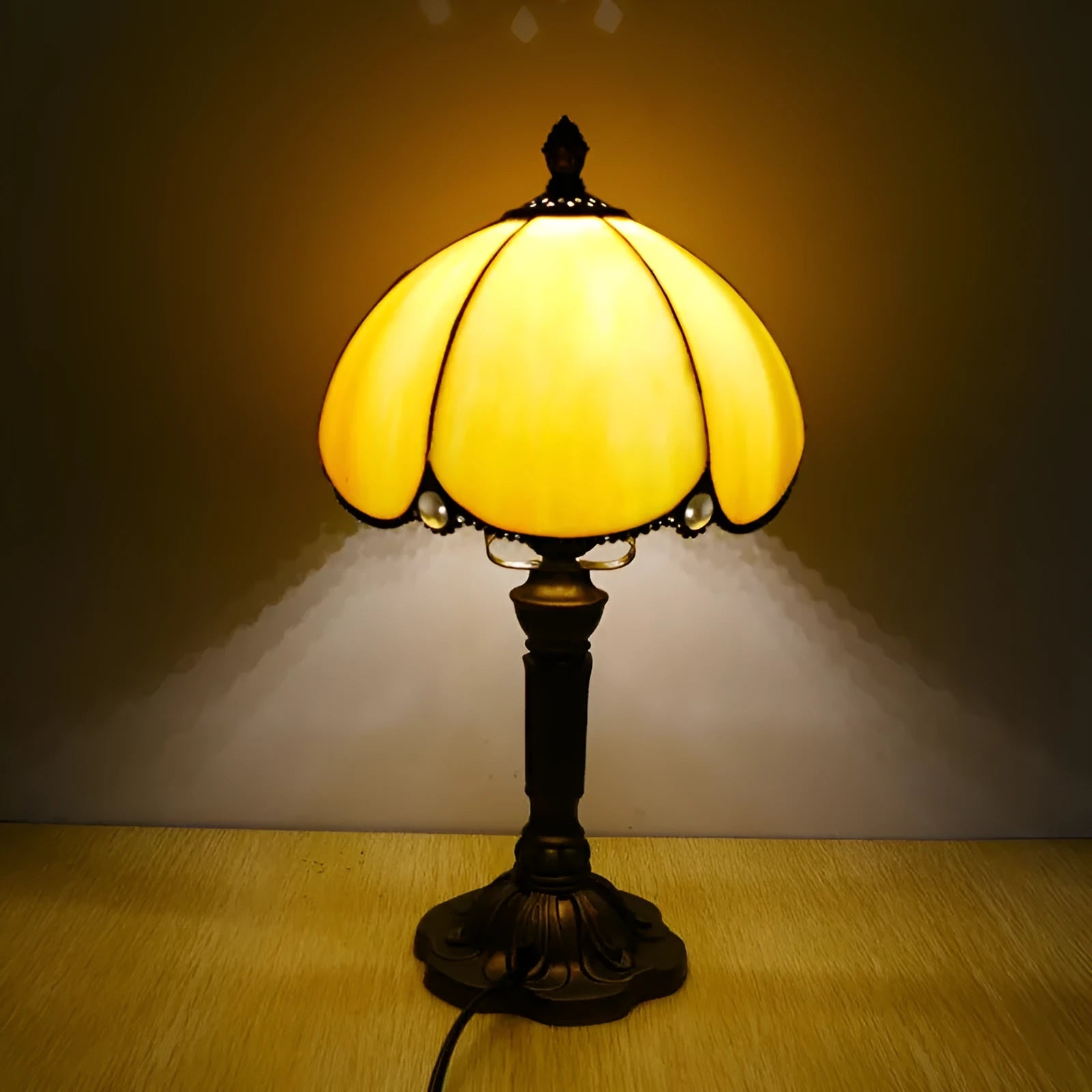 Modern minimalist beige coloured bedside lamp with a width of 20cm on a table.