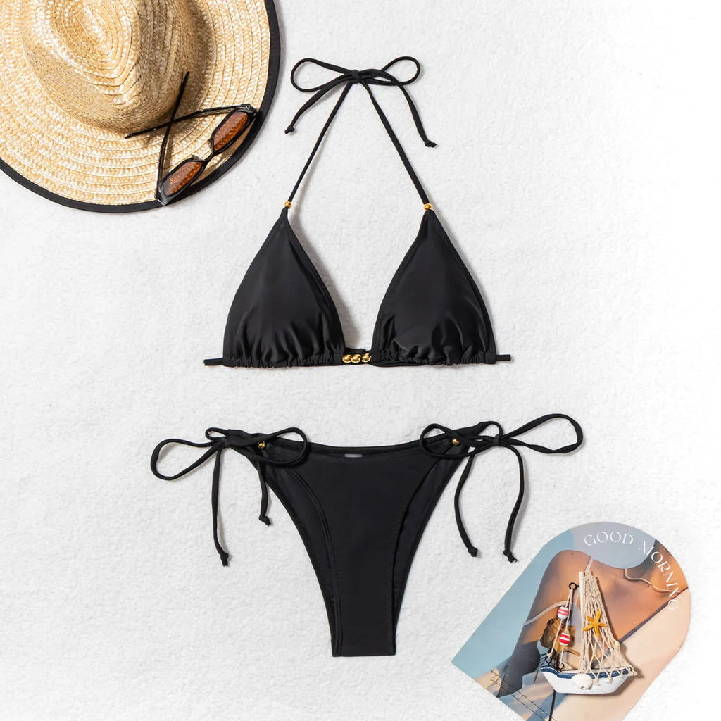 Black women's bikini swimsuit with metal beads on a split skirt.