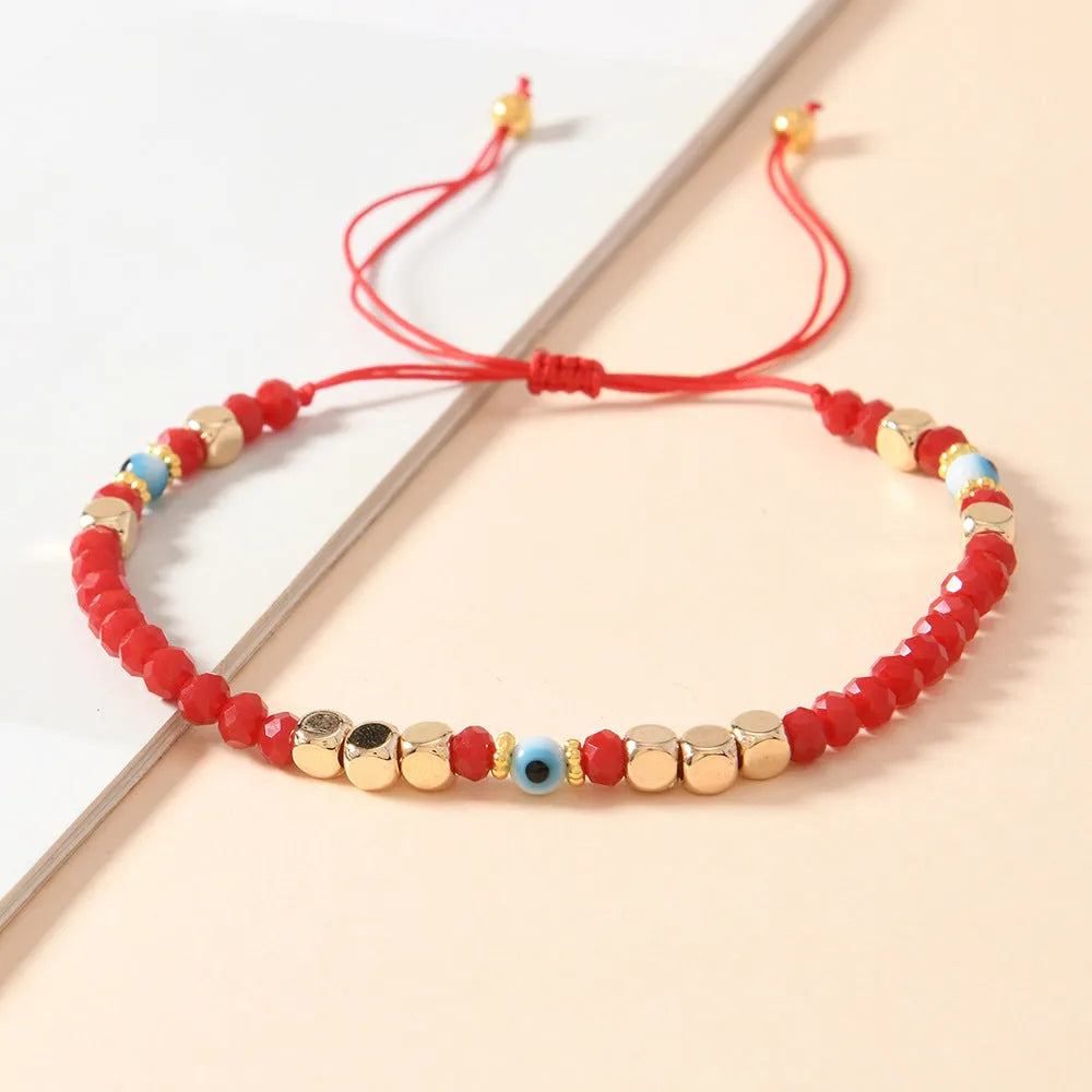 Red hand-woven beaded couple bracelet with artificial crystal eye geometric design on white background
