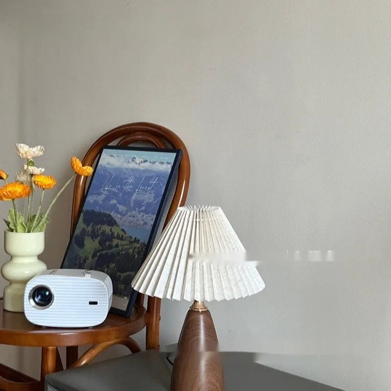 Tapered floral ceramic table lamp with remote control on a wooden surface.