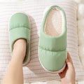 A pair of blue down cotton slippers with a thick sole, artificial leather upper, and plush lining for indoor winter wear.