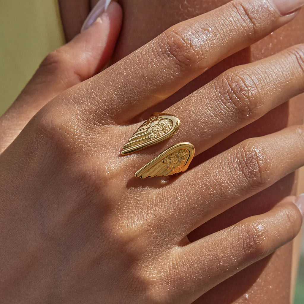 Silver-toned wings design ring with an opening on a white background.