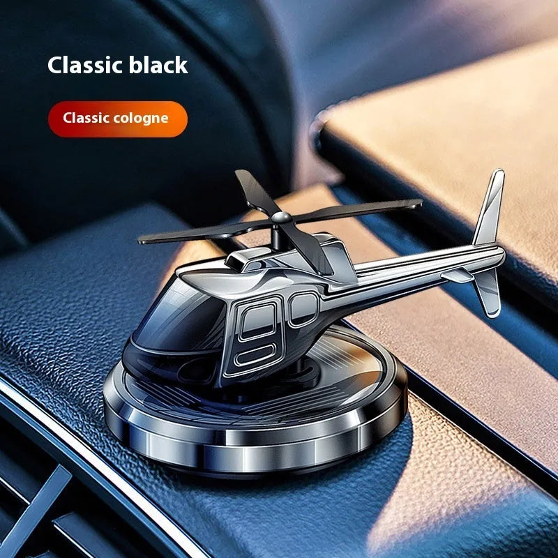 Silver metal solar helicopter car perfume ornament rotating on a car dashboard.