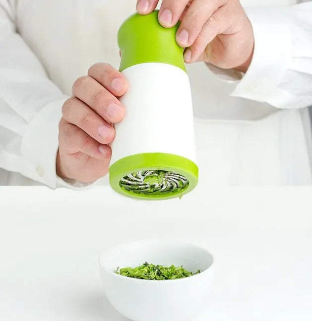 White and silver handheld herb grinder with removable top on a kitchen counter.