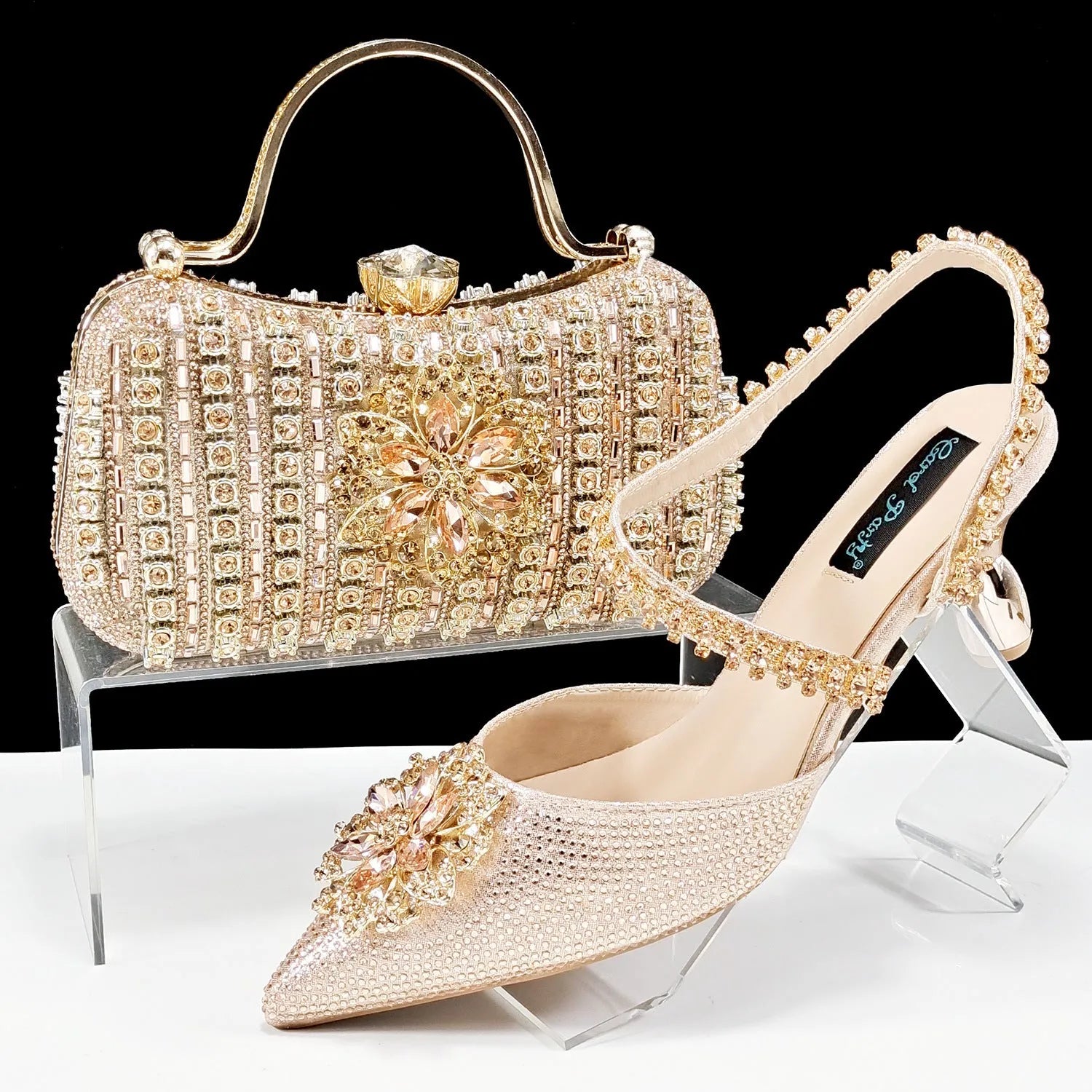 Women's black high heel and clutch bag set with rhinestone ankle chain and floral metal decoration.
