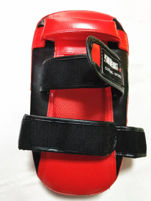 Black and red square martial arts training pad held in hand, showing double buckle strap.