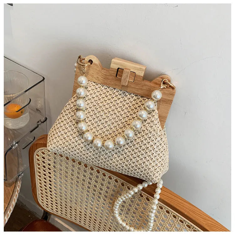 Women's woven straw shoulder bag with pearl chain detail, shown in beige, featuring internal organiser pockets.