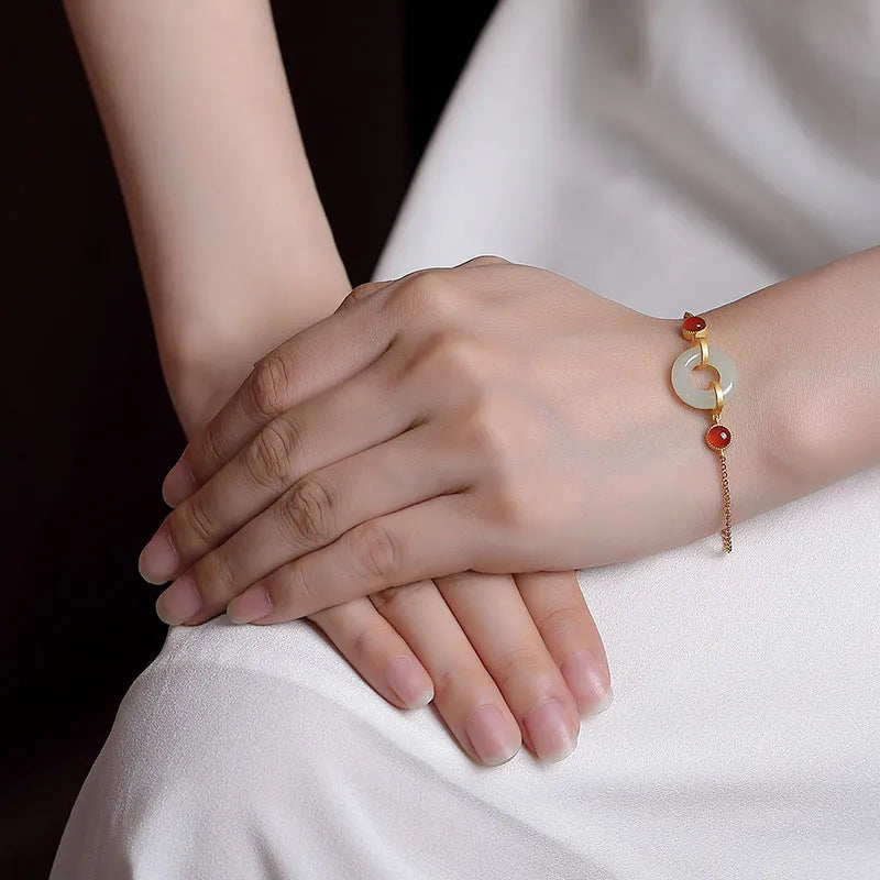 Gold-coloured women's bracelet with a sterling silver base and an inlaid natural Hetian jade peace symbol buckle.