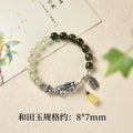 Close-up of a retro women's bracelet with a natural Hetian jade bead and a silver coin pendant on a wrist.