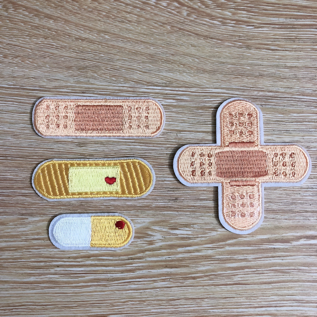 Ten embroidered cloth patch badges with textured threadwork for iron-on or sew-on clothing decoration.