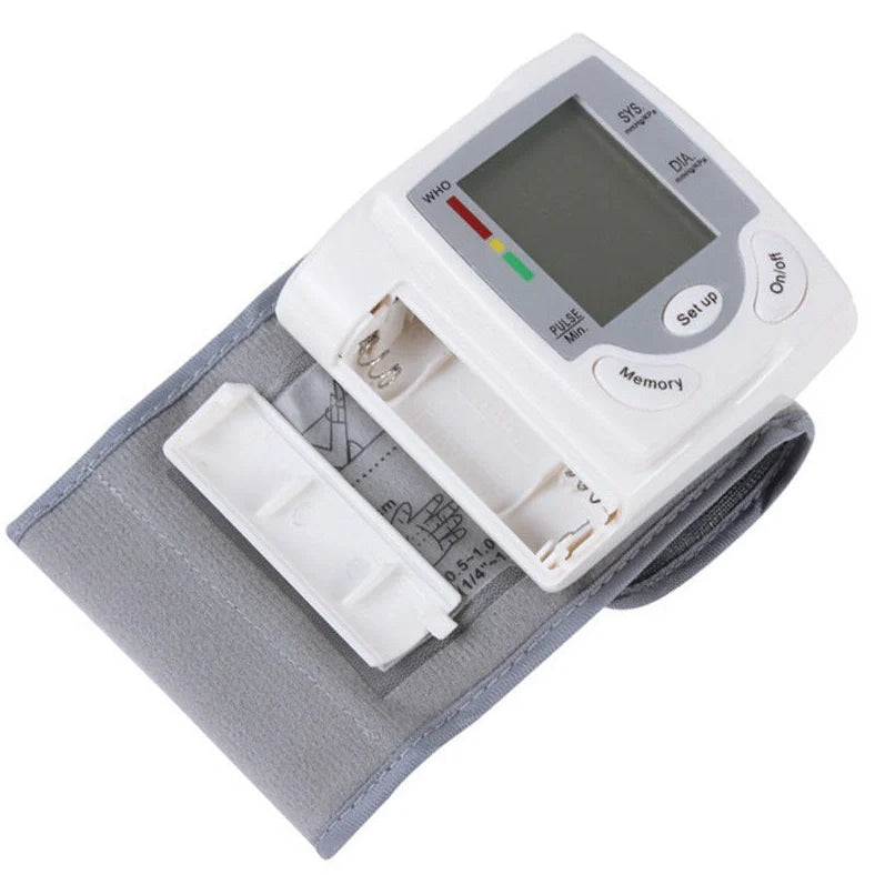 White wrist blood pressure monitor with digital display showing blood pressure readings and adjustable cuff