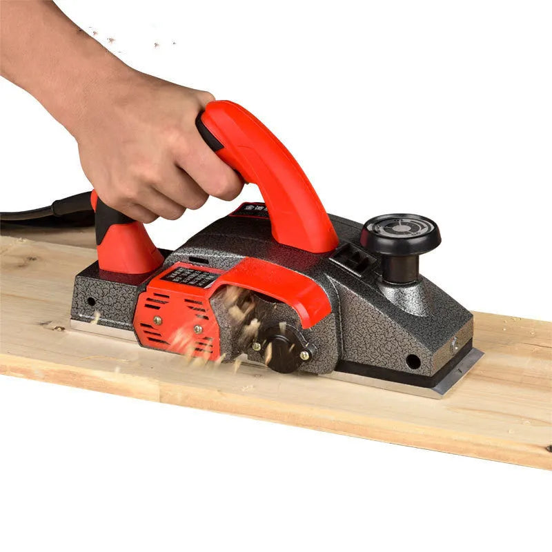 Red desktop electric wood planer with aluminium body showing 82mm planing width and depth adjustment controls