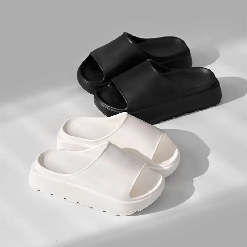 Women's beige thick-soled beach slippers with a fish mouth design on a wooden floor.