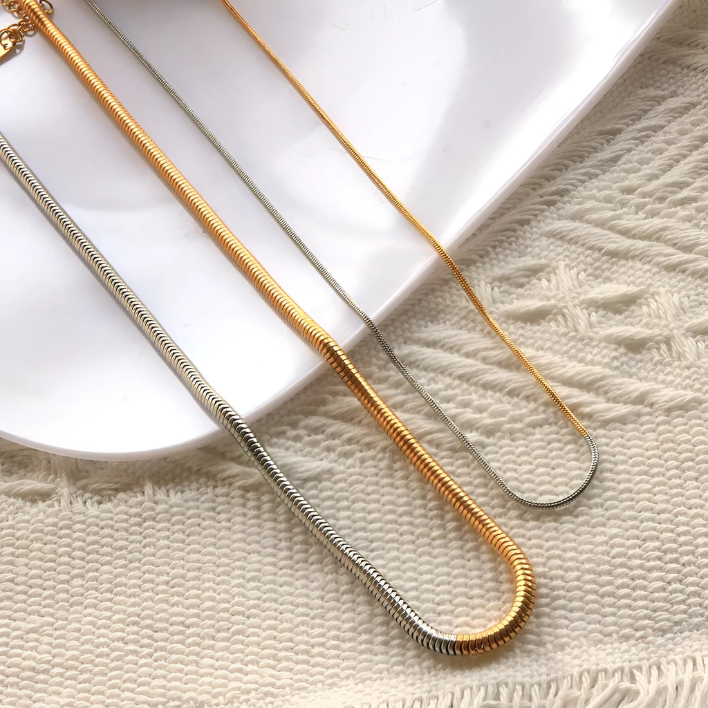 Close-up of a women's golden snake bones chain necklace with geometric lines, 3mm wide.