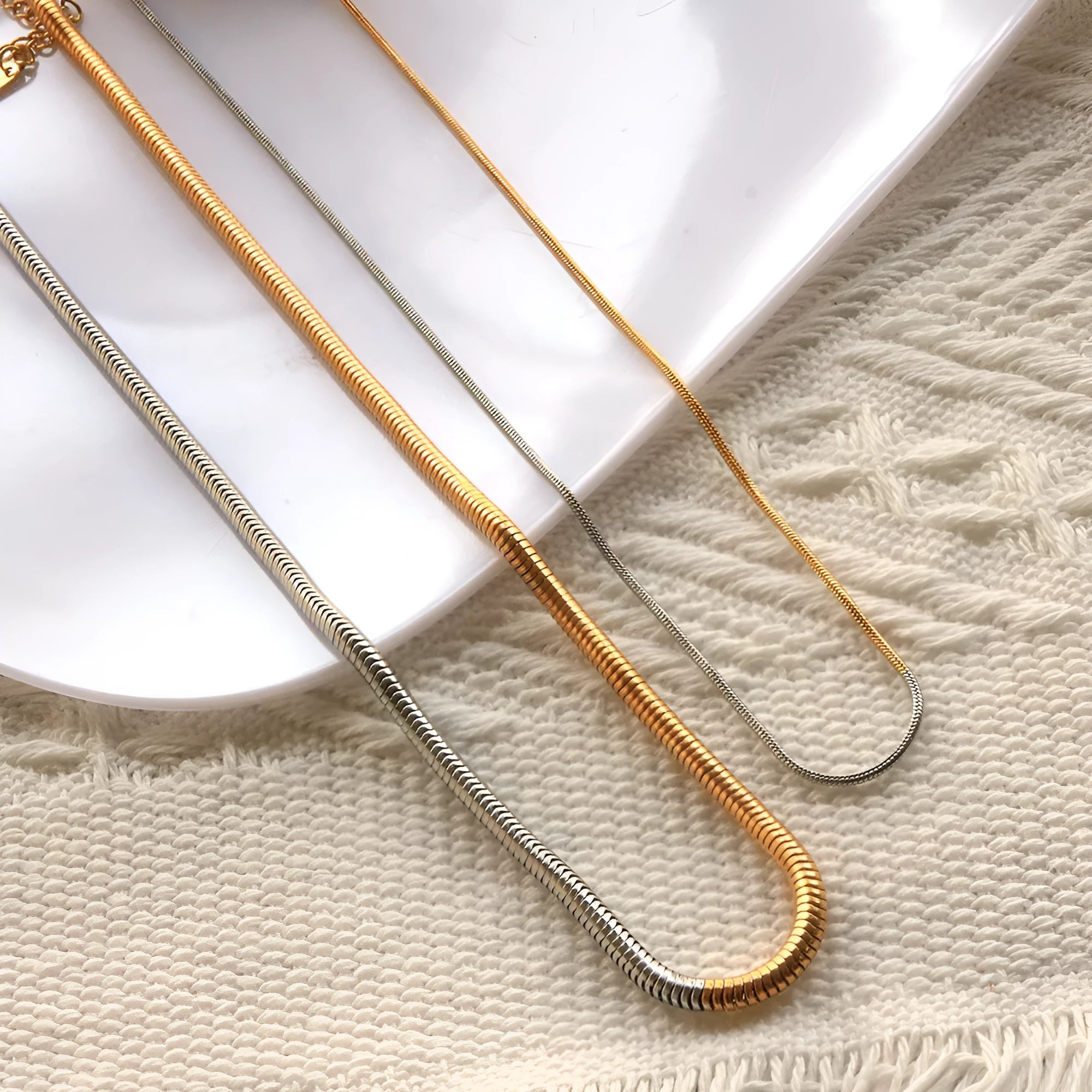 Close-up of a women's golden snake bones chain necklace with geometric lines, 3mm wide.