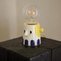 Handmade ceramic bedside lamp with a creative ball headlight design on a wooden table.
