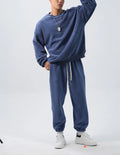 Men's black polar fleece sports suit with crew neck jacket and loose fit trousers laid flat.