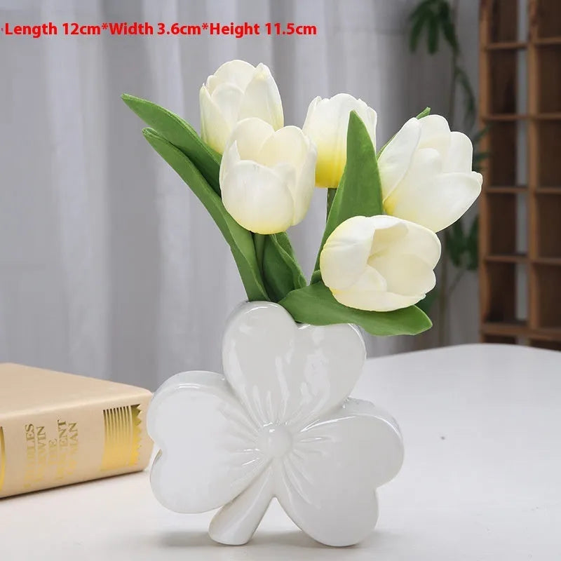Small clover-design ceramic vase in pink, red, light green, or white on a desktop.