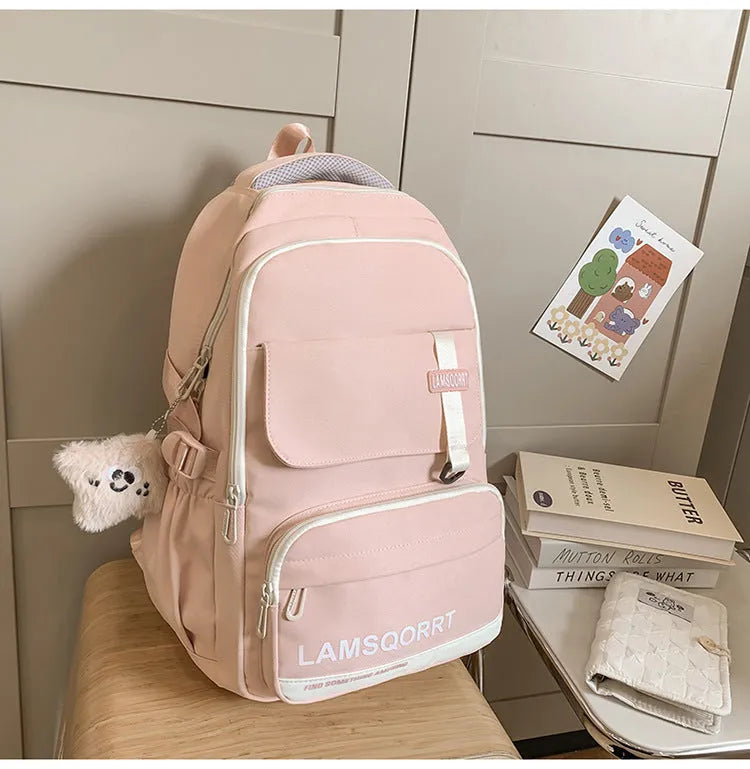 Large black nylon school backpack with curved straps, shown with and without a decorative pendant.