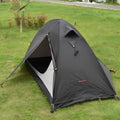 Lightweight red single person tent with aluminium poles pitched outdoors.