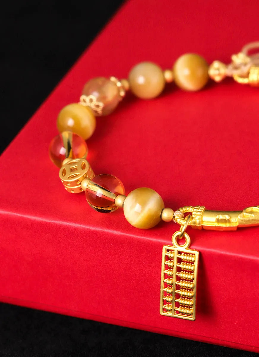 Close-up of a women's beaded bracelet with a diamond-shaped abacus tag bead, tigereye, citrine, and yellow tower crystal stones on copper.
