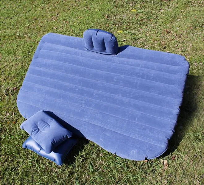 Black inflatable car bed with flocked material set up in the back of a five-seater vehicle, showing two pillows.